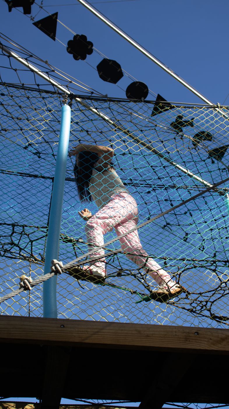 Menina atravessando a rede suspensa do Arvorismo do Dudinha