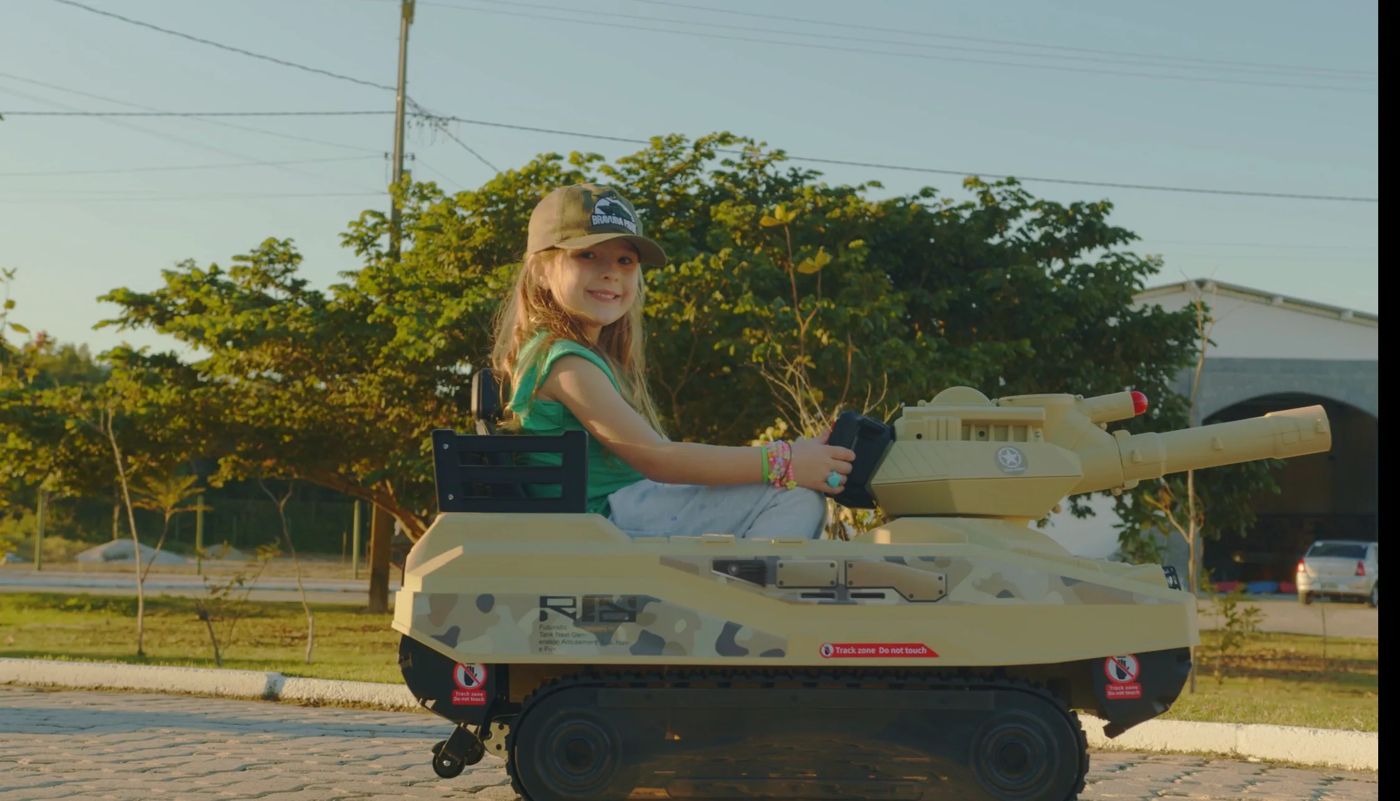 Menina sorrindo no mini tanque do Blindado do Dudinha
